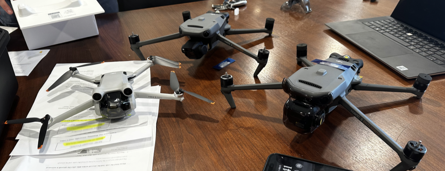 Small drones sitting on a table littered with paperwork.